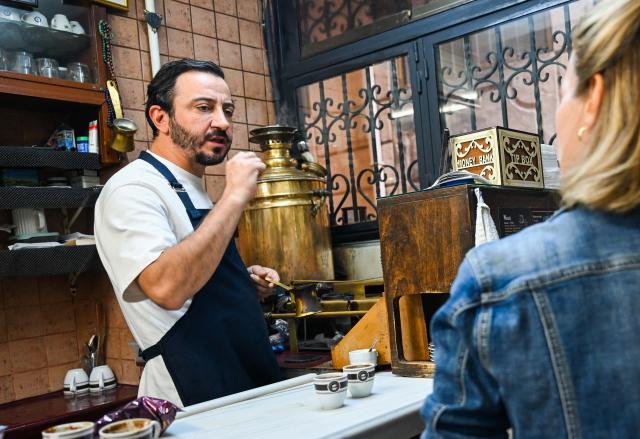 (251214) -- ISTANBUL, Dec. 14, 2025 (Xinhua) -- Can Ozmen (L), owner of a popular Turkish cafe Mandabatmaz, talks with a customer while preparing coffee in Istanbul, Türkiye, Nov. 22, 2025.
  Mandabatmaz, a Turkish cafe, is located in a small alley beside Istiklal Avenue in Istanbul.
  The owner, Can Ozmen, took over this small coffee shop with a history of nearly sixty years from his parents. To carry on the tradition, he still insists on brewing coffee with copper pots. Ozmen introduced that Turkish coffee should be consumed with coffee grounds, which makes Turkish coffee unique. "Unlike other coffees, which are filtered, Turkish coffee is enjoyed in its entirety," Ozmen explained.
  Turkish coffee has a long history and was inscribed on UNESCO's Representative List of the Intangible Cultural Heritage of Humanity in 2013.
  While in China, a riverside cafe in Yunnan also wins fame among coffee lovers.
  Li Jinhe, 53, has operated his cafe in Mangkuan under Baoshan City in Gaoligong Mountains for 14 years.
  His "flame-brewed coffee", which made by a blowtorch to heat beneath siphon pots, has taken the Internet by storm for its originality, turning his cafe into a viral sensation.
  Tourists said that the coffee shop by the Nujiang River has broken the stereotype of urban coffee, and coffee should be a daily drink integrated into life.
  "I grew up here, and love Gaoligong Mountains," said Li. The Gaoligong Mountains, where fertile soil, ideal temperatures and abundant sunlight situate it within the global coffee-growing belt, boast small-bean coffee. "It is my unwavering commitment to promote local small-bean coffee," added Li.
  Although made by different ways, both Turkish and Chinese coffee tell the story of people's pursuit of life with warmth and aroma. (Xinhua/Liu Lei)