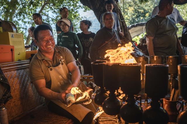 (251214) -- KUNMING, Dec. 14, 2025 (Xinhua) -- Li Jinhe makes coffee at his cafe in Mangkuan Township of Baoshan City, southwest China's Yunnan Province, Nov. 15, 2025.
  Mandabatmaz, a Turkish cafe, is located in a small alley beside Istiklal Avenue in Istanbul.
  The owner, Can Ozmen, took over this small coffee shop with a history of nearly sixty years from his parents. To carry on the tradition, he still insists on brewing coffee with copper pots. Ozmen introduced that Turkish coffee should be consumed with coffee grounds, which makes Turkish coffee unique. "Unlike other coffees, which are filtered, Turkish coffee is enjoyed in its entirety," Ozmen explained.
  Turkish coffee has a long history and was inscribed on UNESCO's Representative List of the Intangible Cultural Heritage of Humanity in 2013.
  While in China, a riverside cafe in Yunnan also wins fame among coffee lovers.
  Li Jinhe, 53, has operated his cafe in Mangkuan under Baoshan City in Gaoligong Mountains for 14 years.
  His "flame-brewed coffee", which made by a blowtorch to heat beneath siphon pots, has taken the Internet by storm for its originality, turning his cafe into a viral sensation.
  Tourists said that the coffee shop by the Nujiang River has broken the stereotype of urban coffee, and coffee should be a daily drink integrated into life.
  "I grew up here, and love Gaoligong Mountains," said Li. The Gaoligong Mountains, where fertile soil, ideal temperatures and abundant sunlight situate it within the global coffee-growing belt, boast small-bean coffee. "It is my unwavering commitment to promote local small-bean coffee," added Li.
  Although made by different ways, both Turkish and Chinese coffee tell the story of people's pursuit of life with warmth and aroma. (Xinhua/Wang Guansen)