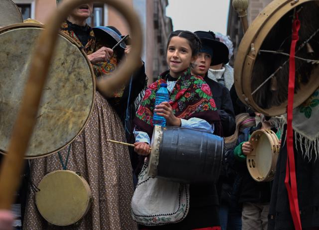 (251215) -- MADRID, Dec. 15, 2025 (Xinhua) -- A girl accompanies the singing with a traditional instrument during a music parade in Madrid, Spain, Dec. 14, 2025. Traditional folk groups and various performance troupes from the Community of Madrid and surrounding provinces marched through the streets on Sunday, playing music and singing together to create a festive atmosphere. (Xinhua/Cheng Min)