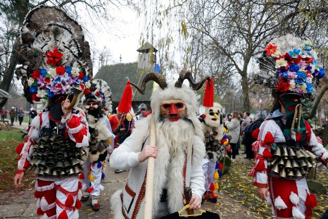 (251215) -- BUCHAREST, Dec. 15, 2025 (Xinhua) -- Masked members of a traditional dance group participate in a parade during the "White Flowers" festival of traditions and customs at the Village Museum in Bucharest, Romania, on Dec. 14, 2025. (Photo by Cristian Cristel/Xinhua)