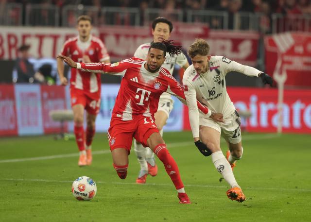 (251215) -- MUNICH, Dec. 15, 2025 (Xinhua) -- Michael Olise (front L) of FC Bayern Munich vies with Nikolas Veratschnig of FSV Mainz 05 during the German first division Bundesliga football match between FC Bayern Munich and FSV Mainz 05 in Munich, Germany, Dec. 14, 2025. (Photo by Philippe Ruiz/Xinhua)