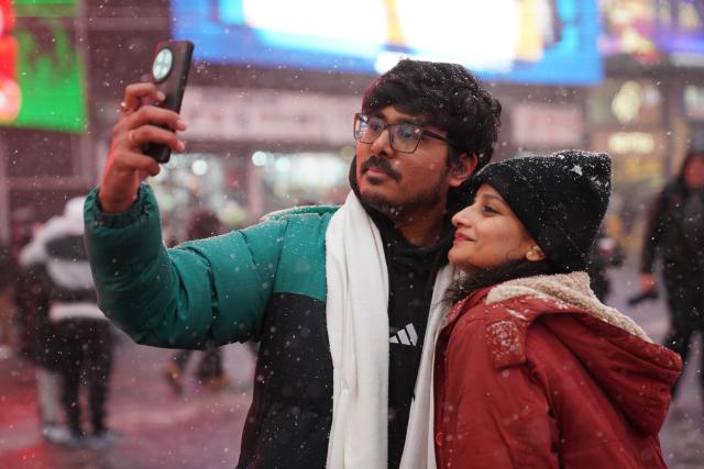 (251215) -- NEW YORK, Dec. 15, 2025 (Xinhua) -- A couple takes a selfie in snow at Times Square in New York, the United States, on Dec. 14, 2025. (Xinhua/Zhang Fengguo)