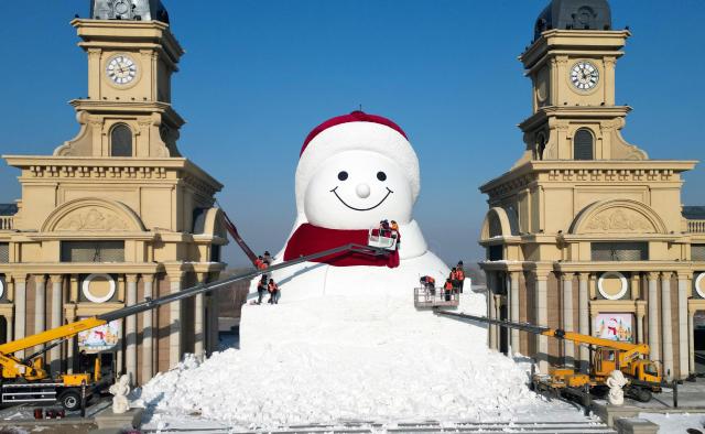 (251215) -- BEIJING, Dec. 15, 2025 (Xinhua) -- A drone photo shows workers building a giant snowman at the Qunli music park in Harbin, northeast China's Heilongjiang Province, Dec. 14, 2025.
  This year's giant snowman, 19 meters in height and made with some 3,000 cubic meters of snow, is one meter taller than that of last year. (Photo by Liu Yang/Xinhua)