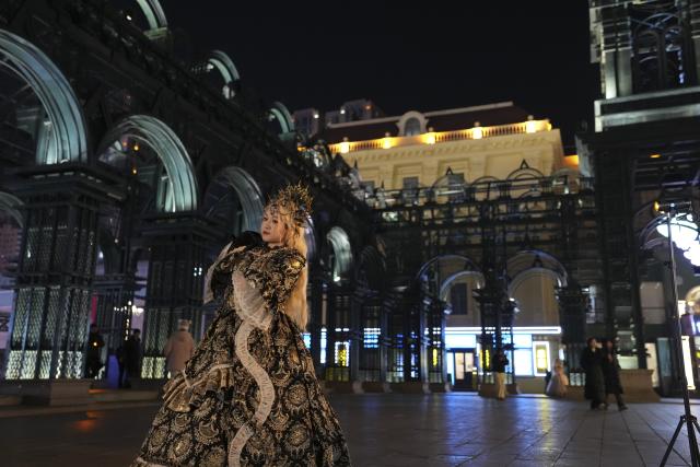 (251215) -- HARBIN, Dec. 15, 2025 (Xinhua) -- A tourist in costume poses for a photo at a square of architecture art in Harbin, northeast China's Heilongjiang Province, Dec. 15, 2025. The square, where the landmark St. Sophia Cathedral, a former Russian Orthodox church and a perfect example of Neo-Byzantine architectures, is located, has become a hot spot for tourists to take travel photos. (Xinhua/Wang Song)
