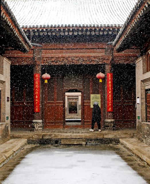 (251216) -- BEIJING, Dec. 16, 2025 (Xinhua) -- A tourist visits a folk custom museum amid snowfall in Dingcun Village, Linfen City of north China's Shanxi Province, Dec. 12, 2025. (Photo by Li Xianjun/Xinhua)