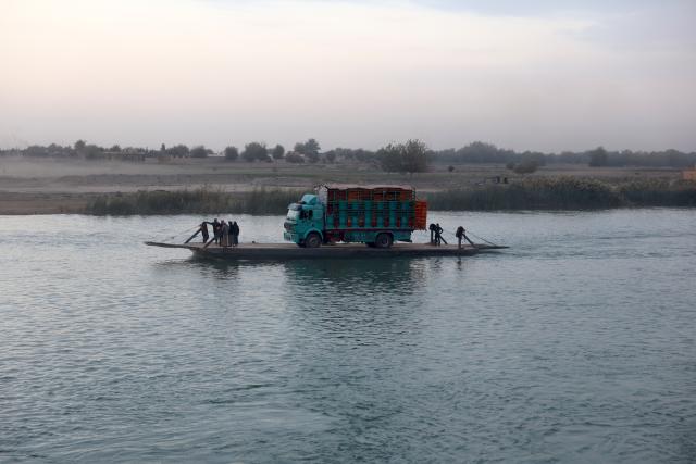 (251216) -- DEIR AL-ZOUR, Dec. 16, 2025 (Xinhua) -- A truck loaded with goods is seen aboard a flat-bottomed ferry crossing the Euphrates River in Deir al-Zour province, eastern Syria, Dec. 12, 2025. TO GO WITH "Feature: Ferries of fear -- war-weary Syrians forced to risk lives on the Euphrates" (Str/Xinhua)