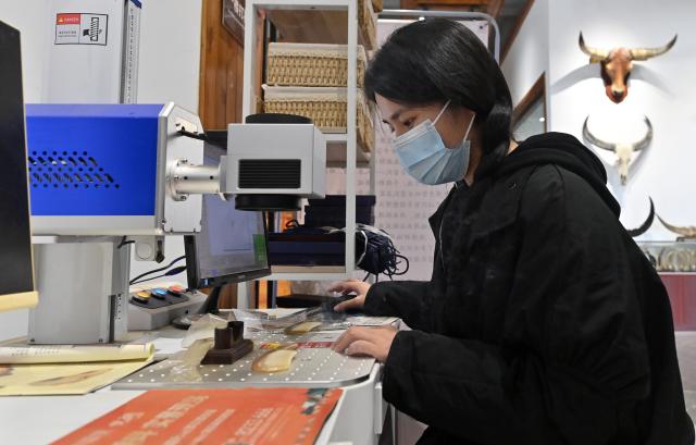 (251216) -- NANNING, Dec. 16, 2025 (Xinhua) -- A worker applies laser engraving on an ox horn comb at an ox horn product base in Wuling Town of Binyang County, south China's Guangxi Zhuang Autonomous Region, Dec. 16, 2025. The Wuling ox horn carving technique of Binyang County is a local traditional craft with a history of over three centuries. In recent years, Binyang County has been encouraging industrial innovation in the development of ox corn products such as combs, massage hammers, tea sets and pen caps. Every year, some six million ox horn products are produced in the county with considerable market acceptance. (Xinhua/Lu Boan)