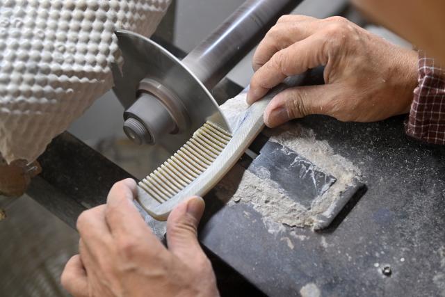 (251216) -- NANNING, Dec. 16, 2025 (Xinhua) -- Ye Hualiang, an inheritor of the Wuling ox horn carving technique, works on an ox horn comb in Wuling Town of Binyang County, south China's Guangxi Zhuang Autonomous Region, Dec. 16, 2025. The Wuling ox horn carving technique of Binyang County is a local traditional craft with a history of over three centuries. In recent years, Binyang County has been encouraging industrial innovation in the development of ox corn products such as combs, massage hammers, tea sets and pen caps. Every year, some six million ox horn products are produced in the county with considerable market acceptance. (Xinhua/Lu Boan)