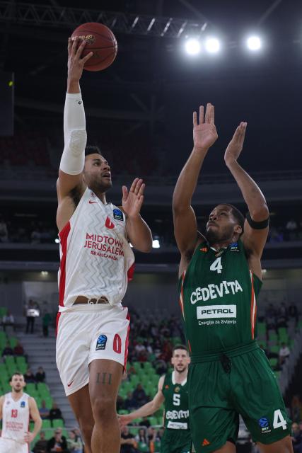 (251217) -- LJUBLJANA, Dec. 17, 2025 (Xinhua) -- Justin Smith (L) of Hapoel Midtown Jerusalem goes for a layup during the BKT EuroCup 2025/26 11th round basketball match between Cedevita Olimpija Ljubljana and Hapoel Midtown Jerusalem in Ljubljana, Slovenia, on Dec. 16, 2025. (Photo by Zeljko Stevanic/Xinhua)