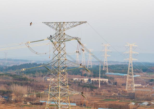 (251217) -- HEFEI, Dec. 17, 2025 (Xinhua) -- A drone photo taken on Dec. 16, 2025 shows constructors working on a power transmission line in east China's Anhui Province. The main-body construction of the 500-kV power transmission line from Xiangjian to Ludao in Anhui Province was successfully completed on Wednesday. With a total length of 136.8 kilometers, the line will further optimize the power grid structure of Anhui and enhance power supply reliability upon completion. (Photo by Zheng Xianlie/Xinhua)