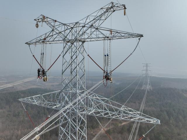 (251217) -- HEFEI, Dec. 17, 2025 (Xinhua) -- A drone photo taken on Dec. 17, 2025 shows constructors working on a power transmission line in east China's Anhui Province. The main-body construction of the 500-kV power transmission line from Xiangjian to Ludao in Anhui Province was successfully completed on Wednesday. With a total length of 136.8 kilometers, the line will further optimize the power grid structure of Anhui and enhance power supply reliability upon completion. (Photo by Zhao Xianfu/Xinhua)