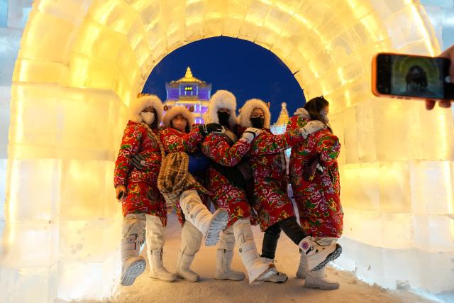 (251217) -- HARBIN, Dec. 17, 2025 (Xinhua) -- Tourists pose for group photos at the Harbin Ice-Snow World in Harbin, northeast China's Heilongjiang Province, Dec. 17, 2025. The Harbin Ice-Snow World, world's largest ice and snow theme park, officially opened for the season on Wednesday, unveiling its most spectacular edition yet, featuring landmark attractions, thoughtful services and magnificent ice sculptures across a record 1.2 million square meters of park area. (Xinhua/Wang Jianwei)