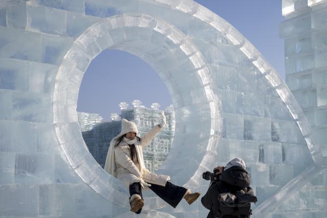 (251217) -- HARBIN, Dec. 17, 2025 (Xinhua) -- A tourist poses for photos at the Harbin Ice-Snow World in Harbin, northeast China's Heilongjiang Province, Dec. 17, 2025. The Harbin Ice-Snow World, world's largest ice and snow theme park, officially opened for the season on Wednesday, unveiling its most spectacular edition yet, featuring landmark attractions, thoughtful services and magnificent ice sculptures across a record 1.2 million square meters of park area. (Xinhua/Zhang Tao)