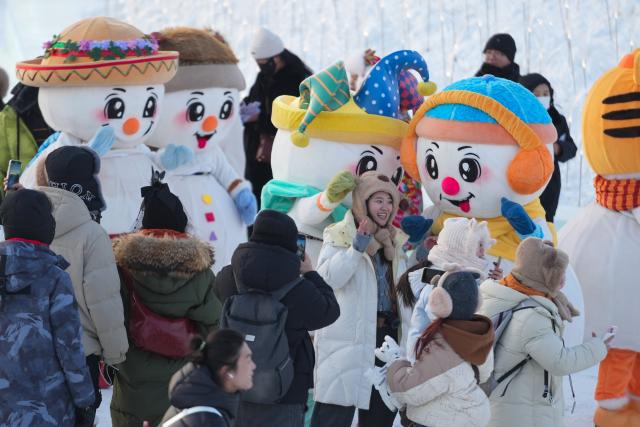 (251217) -- HARBIN, Dec. 17, 2025 (Xinhua) -- Tourists take photos at the Harbin Ice-Snow World in Harbin, northeast China's Heilongjiang Province, Dec. 17, 2025. The Harbin Ice-Snow World, world's largest ice and snow theme park, officially opened for the season on Wednesday, unveiling its most spectacular edition yet, featuring landmark attractions, thoughtful services and magnificent ice sculptures across a record 1.2 million square meters of park area. (Xinhua/Wang Jianwei)
