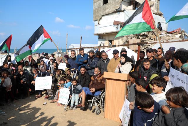 (251217) -- GAZA, Dec. 17, 2025 (Xinhua) -- Palestinians in the Al-Shati refugee camp west of Gaza City hold signs and chant slogans demanding the provision of temporary housing as the winter weather continues to hit the region, Dec. 17, 2025. (Photo by Rizek Abdeljawad/Xinhua)