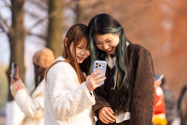(251218) -- CHANGSHA, Dec. 18, 2025 (Xinhua) -- People take photos as they visit a park, where metasequoia tree leaves have turned red, in Changsha, central China's Hunan Province, Dec. 18, 2025. (Xinhua/Chen Sihan)