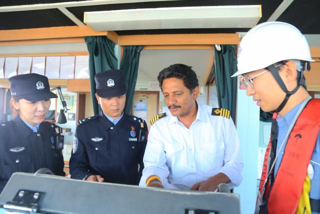 (251218) -- HAIKOU, Dec. 18, 2025 (Xinhua) -- Border inspection officers learn about a ship from its foreign captain in Yangpu of Danzhou, south China's Hainan Province, Dec. 18, 2025. China on Thursday launched island-wide special customs operations in the Hainan Free Trade Port (FTP). (Photo by Wu Yue/Xinhua)