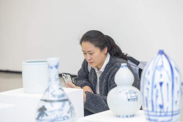 (251218) -- CHONGQING, Dec. 18, 2025 (Xinhua) -- A visitor takes photos of an artwork at an exhibition of children's arts at Sichuan Fine Arts Institute in southwest China's Chongqing, Dec. 18, 2025. This international exhibition of children's arts as part of the 4th China-Europe Humanities and Arts Education Forum opened here on Thursday, featuring 360 artworks by artists aged 3 to 18 from 25 countries. (Xinhua/Huang Wei)