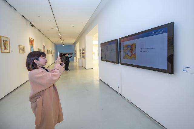 (251218) -- CHONGQING, Dec. 18, 2025 (Xinhua) -- A visitor takes photos of an artwork at an exhibition of children's arts at Sichuan Fine Arts Institute in southwest China's Chongqing, Dec. 18, 2025. This international exhibition of children's arts as part of the 4th China-Europe Humanities and Arts Education Forum opened here on Thursday, featuring 360 artworks by artists aged 3 to 18 from 25 countries. (Xinhua/Huang Wei)