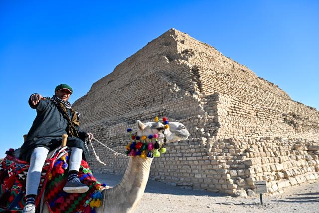 (251218) -- SAQQARA, Dec. 18, 2025 (Xinhua) -- A man rides a camel in front of the Step Pyramid in the Saqqara necropolis, Giza, Egypt, Dec. 18, 2025. (Xinhua/Xin Mengchen)