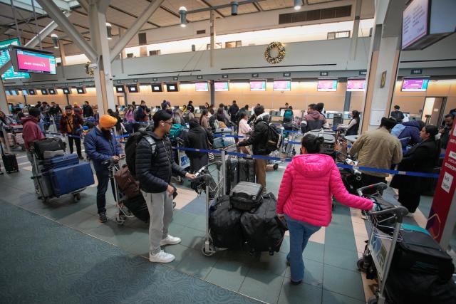 (251219) -- RICHMOND, Dec. 19, 2025 (Xinhua) -- Passengers line up to check in at Vancouver International Airport in Richmond, British Columbia, Canada, Dec. 18, 2025. Winter holiday travel season has come, Vancouver International Airport handled more than 76,800 passenger trips on Thursday. (Photo by Liang Sen/Xinhua)
