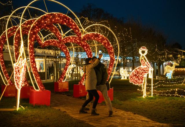 (251219) -- PRAGUE, Dec. 19, 2025 (Xinhua) -- People pose for selfies at the Story of Lights themed park in Prague, the Czech Republic, Dec. 19, 2025. An Europe-themed light park illuminates the banks of the Vltava River in Prague, offering visitors an immersive journey of architecture and light. (Photo by Dana Kesnerova/Xinhua)