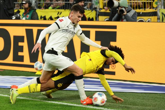 (251220) -- DORTMUND, Dec. 20, 2025 (Xinhua) -- Karim Adeyemi (bottom) of Borussia Dortmund vies with Yannik Engelhardt of Borussia Moenchengladbach during the German first division Bundesliga football match between Borussia Dortmund and Borussia Moenchengladbach in Dortmund, Germany, Dec. 19, 2025. (Photo by Joachim Bywaletz/Xinhua)