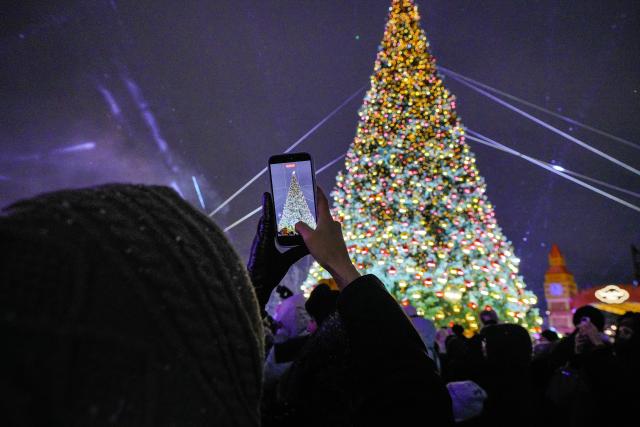 (251220) -- ASTANA, Dec. 20, 2025 (Xinhua) -- A resident shoots a video as a New Year tree is lit up in Astana, Kazakhstan, Dec. 19, 2025. A New Year tree lighting ceremony was held in Astana on Friday, with more than 40 large New Year trees lit up across the city. The ceremony was accompanied by a citywide "fairy-tale fest" featuring concerts, dance performances and fireworks. (Photo by Kalizhan Ospanov/Xinhua)