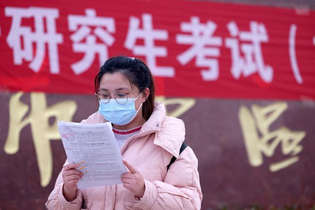 (251220) -- BEIJING, Dec. 20, 2025 (Xinhua) -- An examinee reviews her study materials before entering an examination site for the 2026 postgraduate entrance exam in Zaozhuang, east China's Shandong Province, Dec. 20, 2025. China's national exam for postgraduate enrolment kicked off on Saturday. (Photo by Sun Zhongzhe/Xinhua)