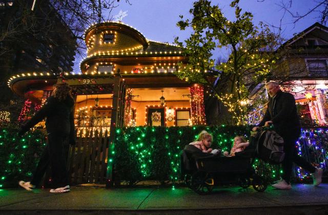 (251220) -- VANCOUVER, Dec. 20, 2025 (Xinhua) -- People walk past a house decorated with Christmas lights in Vancouver, British Columbia, Canada, Dec. 19, 2025. (Photo by Liang Sen/Xinhua)