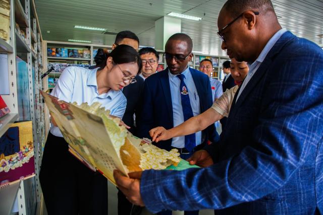 (251220) -- DAR ES SALAAM, Dec. 20, 2025 (Xinhua) -- A staff member from the donating organization shows a book to recipients in Dar es Salaam, Tanzania, Dec. 19, 2025. China Communications Construction Company (CCCC) Tanzania branch on Friday donated 300 books to Tanzania's University of Dar es Salaam, cementing cultural and educational exchanges between the two countries.
   TO GO WITH "Chinese company donates 300 books to Tanzania's University of Dar es Salaam" (Xinhua/Emmanuel Herman)