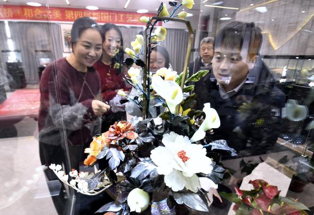 (251220) -- BEIJING, Dec. 20, 2025 (Xinhua) -- Visitors view a piece of jade carving work at an exhibition of intangible cultural heritages in Beijing, capital of China, Dec. 19, 2025.
  The exhibition showcases more than 500 pieces of artworks by inheritors of intangible cultural heritages nationwide. (Xinhua/Li Xin)
