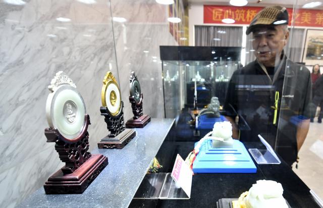 (251220) -- BEIJING, Dec. 20, 2025 (Xinhua) -- A visitor views jade carving works at an exhibition of intangible cultural heritages in Beijing, capital of China, Dec. 19, 2025.
  The exhibition showcases more than 500 pieces of artworks by inheritors of intangible cultural heritages nationwide. (Xinhua/Li Xin)