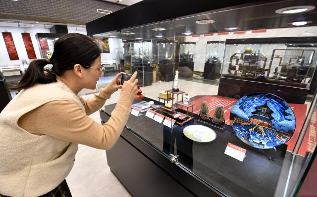 (251220) -- BEIJING, Dec. 20, 2025 (Xinhua) -- A visitor takes photos of artworks at an exhibition of intangible cultural heritages in Beijing, capital of China, Dec. 19, 2025.
  The exhibition showcases more than 500 pieces of artworks by inheritors of intangible cultural heritages nationwide. (Xinhua/Li Xin)