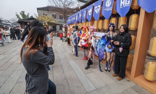 (251220) -- TONGXIANG, Dec. 20, 2025 (Xinhua) -- A tourist (1st R) poses for photos with cosplayers in Tongxiang, east China's Zhejiang Province, Dec. 20, 2025. The festival kicked off here on Saturday and will last until Dec. 28. (Xinhua/Xu Yu)
