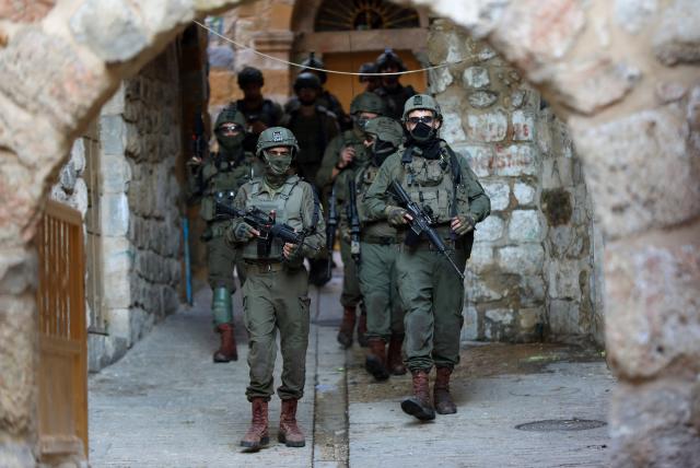 (251221) -- HEBRON, Dec. 21, 2025 (Xinhua) -- Members of Israeli forces secure the streets for Israeli settlers in the Old City of Hebron in the southern West Bank, on Dec. 20, 2025. (Photo by Mamoun Wazwaz/Xinhua)