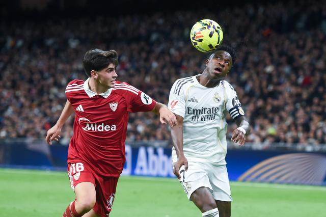 (251221) -- MADRID, Dec. 21, 2025 (Xinhua) -- Real Madrid's Vinicius Junior (R) vies with Sevilla FC's Juanlu Sanchez during a La Liga football match between Real Madrid and Sevilla FC at Santiago Bernabeu stadium in Madrid, Spain, on Dec. 20, 2025. (Photo by Gustavo Valiente/Xinhua)