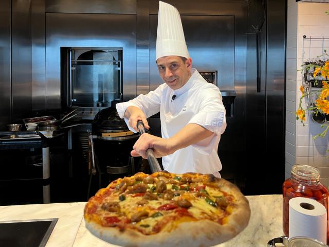 (251221) -- CHONGQING, Dec. 21, 2025 (Xinhua) -- Francesco Sanna presents a Chongqing spicy chicken pizza at the Niccolo Hotel in Chongqing, southwest China, Dec. 12, 2025. TO GO WITH "Feature: Italian chef cooks up culinary dialogue in China" (Xinhua/Yang Shiyan)