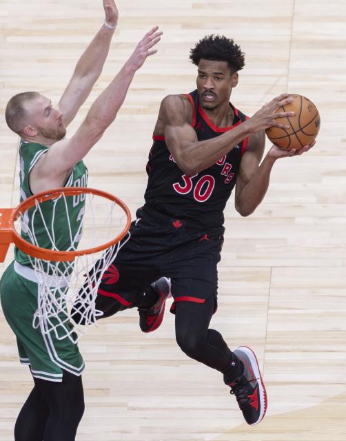 (251221) -- TORONTO, Dec. 21, 2025 (Xinhua) -- Ochai Agbaji (R) of Toronto Raptors goes for a layup during the 2025-2026 NBA regular season game between Toronto Raptors and Boston Celtics in Toronto, Canada, on Dec. 20, 2025. (Xinhua/Zou Zheng)