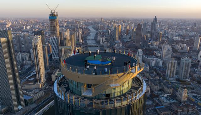 (251221) -- TIANJIN, Dec. 21, 2025 (Xinhua) -- An aerial drone photo taken on Dec. 20, 2025 shows visitors enjoying the urban view at the Jinwan Yunding sightseeing deck in Heping District of Tianjin, north China. Recently, the Jinwan Yunding sightseeing deck, located at the Jinwan Plaza in Heping District of Tianjin, has begun operation. Visitors can ascend to the 300-meter-high rooftop to overlook Tianjin's urban view. (Xinhua/Zhao Zishuo)