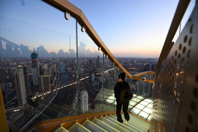 (251221) -- TIANJIN, Dec. 21, 2025 (Xinhua) -- A visitor walks upstairs to the Jinwan Yunding sightseeing deck in Heping District of Tianjin, north China on Dec. 20, 2025. Recently, the Jinwan Yunding sightseeing deck, located at the Jinwan Plaza in Heping District of Tianjin, has begun operation. Visitors can ascend to the 300-meter-high rooftop to overlook Tianjin's urban view. (Xinhua/Zhao Zishuo)