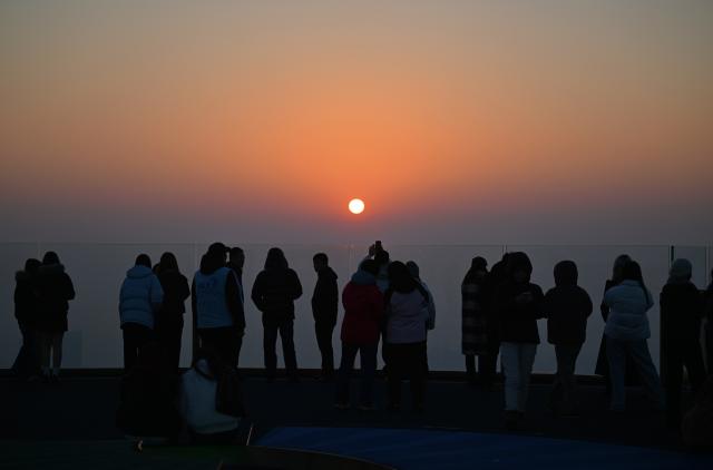 (251221) -- TIANJIN, Dec. 21, 2025 (Xinhua) -- Visitors watch sunset at the Jinwan Yunding sightseeing deck in Heping District of Tianjin, north China on Dec. 17, 2025. Recently, the Jinwan Yunding sightseeing deck, located at the Jinwan Plaza in Heping District of Tianjin, has begun operation. Visitors can ascend to the 300-meter-high rooftop to overlook Tianjin's urban view. (Xinhua/Li Ran)