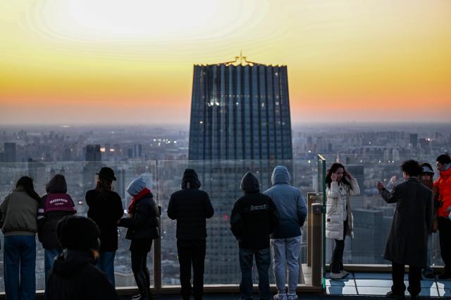 (251221) -- TIANJIN, Dec. 21, 2025 (Xinhua) -- Visitors enjoy the urban view at sunset at the Jinwan Yunding sightseeing deck in Heping District of Tianjin, north China on Dec. 20, 2025. Recently, the Jinwan Yunding sightseeing deck, located at the Jinwan Plaza in Heping District of Tianjin, has begun operation. Visitors can ascend to the 300-meter-high rooftop to overlook Tianjin's urban view. (Xinhua/Zhao Zishuo)