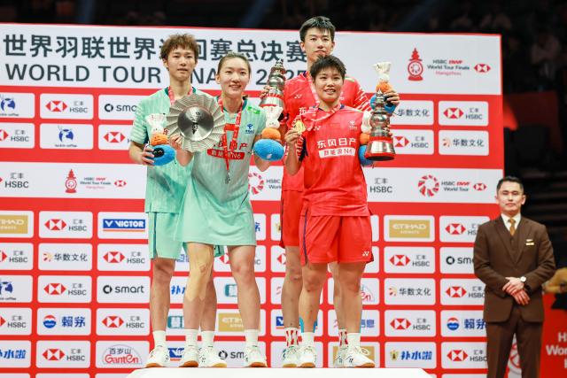 (251221) -- HANGZHOU, Dec. 21, 2025 (Xinhua) -- Gold medalists Feng Yanzhe (R, rear)/Huang Dongping (R, front) of China and silver medalists Jiang Zhenbang (L, rear)/Wei Yaxin of China pose during the awarding ceremony after the mixed doubles final match at BWF World Tour Finals 2025 in Hangzhou, east China's Zhejiang Province, Dec. 21, 2025. (Xinhua/Jiang Han)