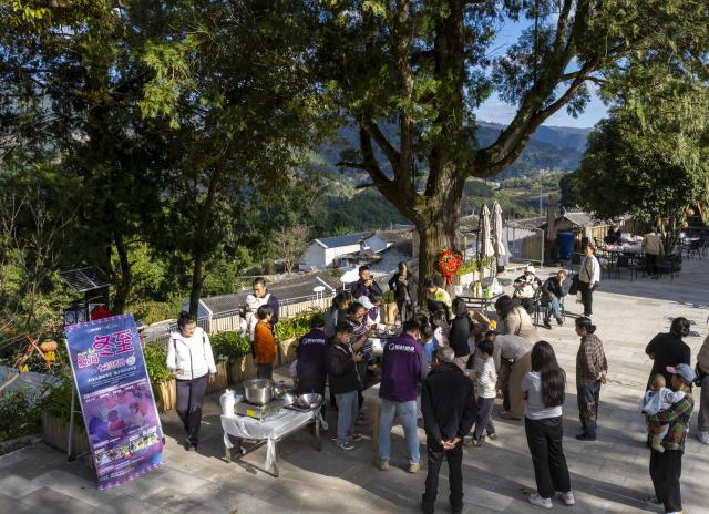 (251221) -- MOJIANG, Dec. 21, 2025 (Xinhua) -- Tourists experience making glutinous dumplings in Manhai Village, Mojiang Hani Autonomous County of Pu'er City, southwest China's Yunnan Province, Dec. 20, 2025. Manhai Village, located in Mojiang Hani Autonomous County of Pu'er City, is home to people from various ethnic groups. In recent years, with the help of the local government, the village has made significant strides in rural revitalization. 
  Manhai has converted idle houses into homestays and study tour centers. The village has also leveraged its intangible cultural heritage, such as bamboo weaving, to develop study tour classes and cultural and creative products. Furthermore, Manhai has trained villagers to run homestays and act as instructors during study tours. 
  Nowadays, the village has attracted many tourists and entrepreneurs to visit and start businesses. (Xinhua/Chen Xinbo)