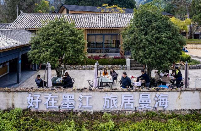 (251221) -- MOJIANG, Dec. 21, 2025 (Xinhua) -- Tourists enjoy their time in Manhai Village, Mojiang Hani Autonomous County of Pu'er City, southwest China's Yunnan Province, Dec. 20, 2025. Manhai Village, located in Mojiang Hani Autonomous County of Pu'er City, is home to people from various ethnic groups. In recent years, with the help of the local government, the village has made significant strides in rural revitalization. 
  Manhai has converted idle houses into homestays and study tour centers. The village has also leveraged its intangible cultural heritage, such as bamboo weaving, to develop study tour classes and cultural and creative products. Furthermore, Manhai has trained villagers to run homestays and act as instructors during study tours. 
  Nowadays, the village has attracted many tourists and entrepreneurs to visit and start businesses. (Xinhua/Chen Xinbo)