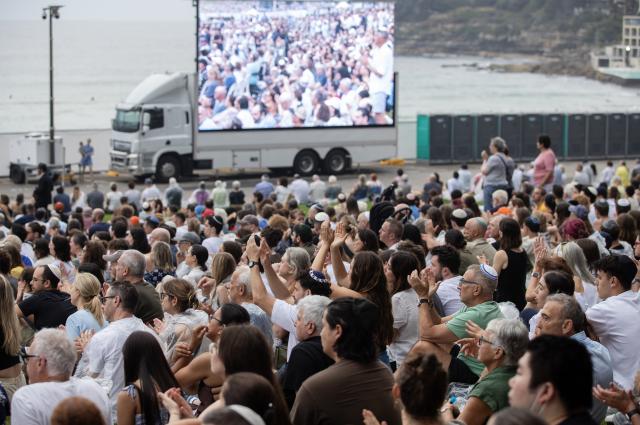 (251221) -- SYDNEY, Dec. 21, 2025 (Xinhua) -- People gather at Bondi Beach for a memorial service to honor the victims of the deadly terror attack a week earlier in Sydney, Australia, Dec. 21, 2025, the National Day of Reflection. (Xinhua/Ma Ping)