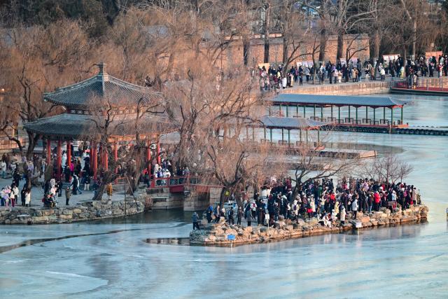 (251221) -- BEIJING, Dec. 21, 2025 (Xinhua) -- Visitors take pictures of the Seventeen-Arch Bridge at the Summer Palace in Beijing, capital of China, Dec. 21, 2025. (Xinhua/Chen Yehua)