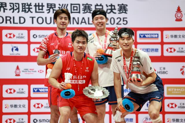 (251221) -- HANGZHOU, Dec. 21, 2025 (Xinhua) -- Winner Kim Won Ho (front R)/Seo Seung Jae of South Korea and runner-up Liang Weikeng (front L)/Wang Chang of China pose at the awarding ceremony after the men's doubles final match at BWF World Tour Finals 2025 in Hangzhou, east China's Zhejiang Province, Dec. 21, 2025. (Xinhua/Jiang Han)