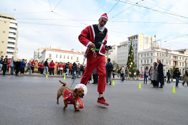 (251221) -- ATHENS, Dec. 21, 2025 (Xinhua) -- A man and his pet dog participate in the Athens Santa Run 2025 in Athens, Greece, Dec. 21, 2025. Thousands of participants dressed as Santa Claus joined the annual Athens Santa Run, a festive and charitable 2.8-km race. (Xinhua/Marios Lolos)